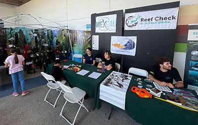 Reef Check exhibit at a marine conservation event with staff and educational materials.