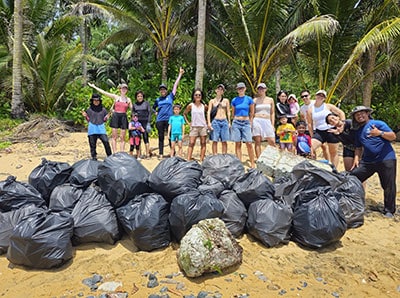 Volunteers cleaning up beach with trash bags and coral reef conservation efforts.