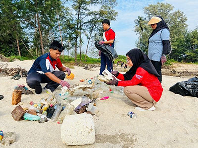 Volunteers sorting marine debris on a sandy beach for reef conservation efforts.